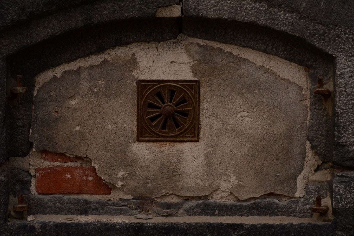 a brick wall with a metal vent in the center