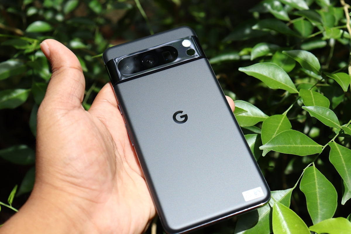 A hand holding a samsung note 8 in front of a bush