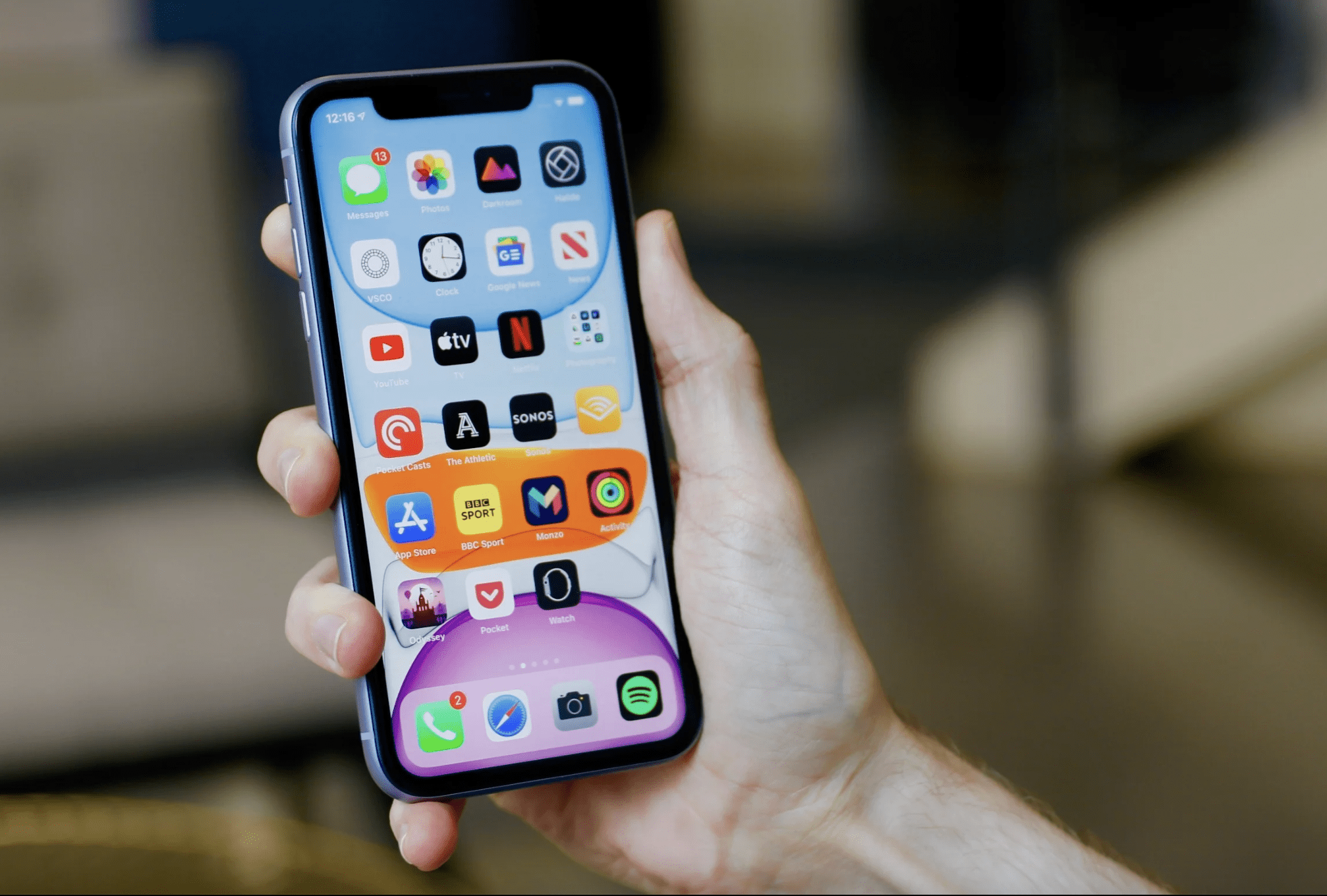 un iphone 11 siendo sostenido con una mano con su pantalla de inicio encendida