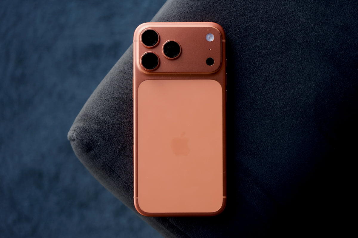 Rose gold smartphone resting on a dark blue surface.