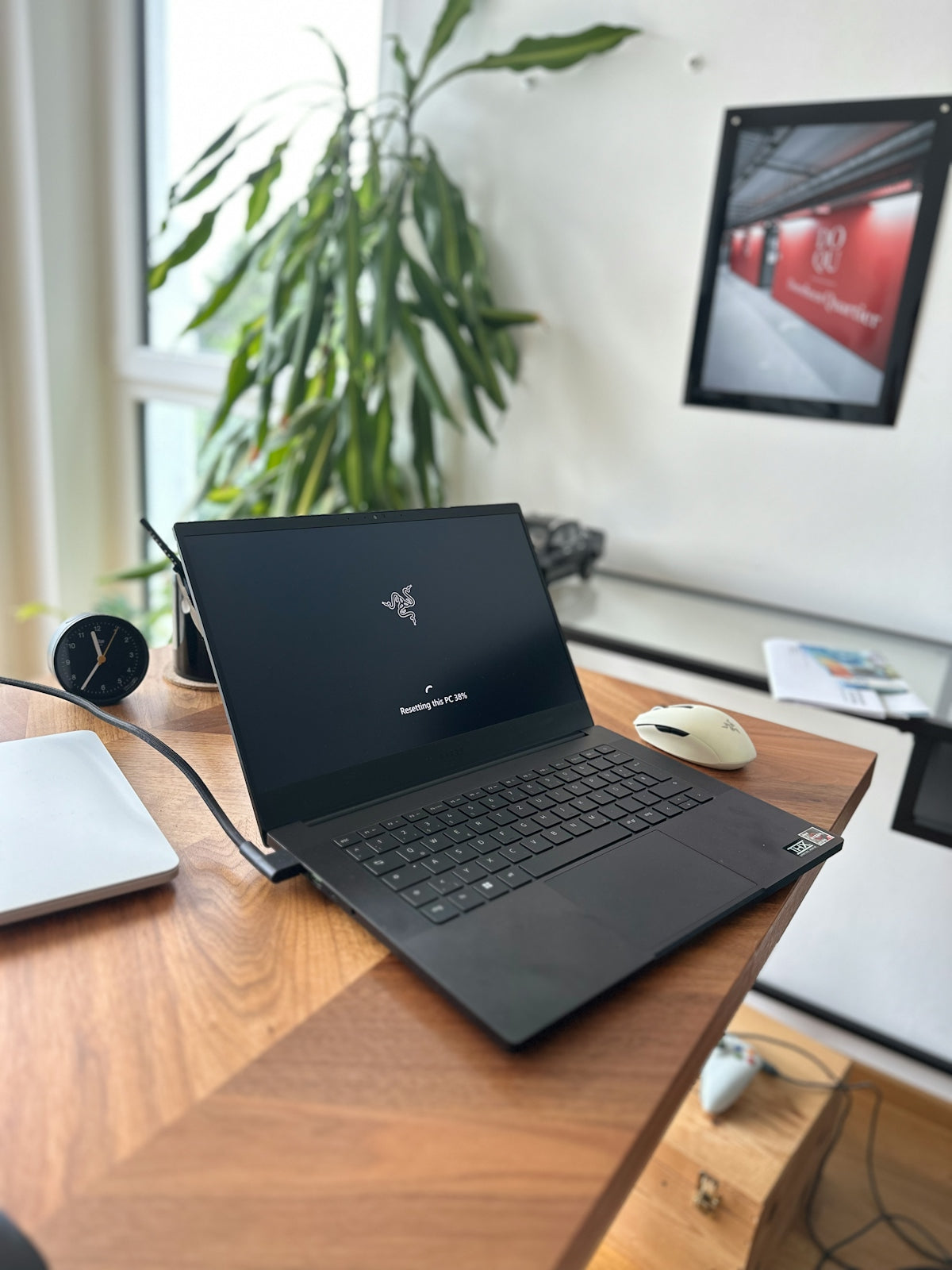 Open black laptop on a wooden desk with plant.